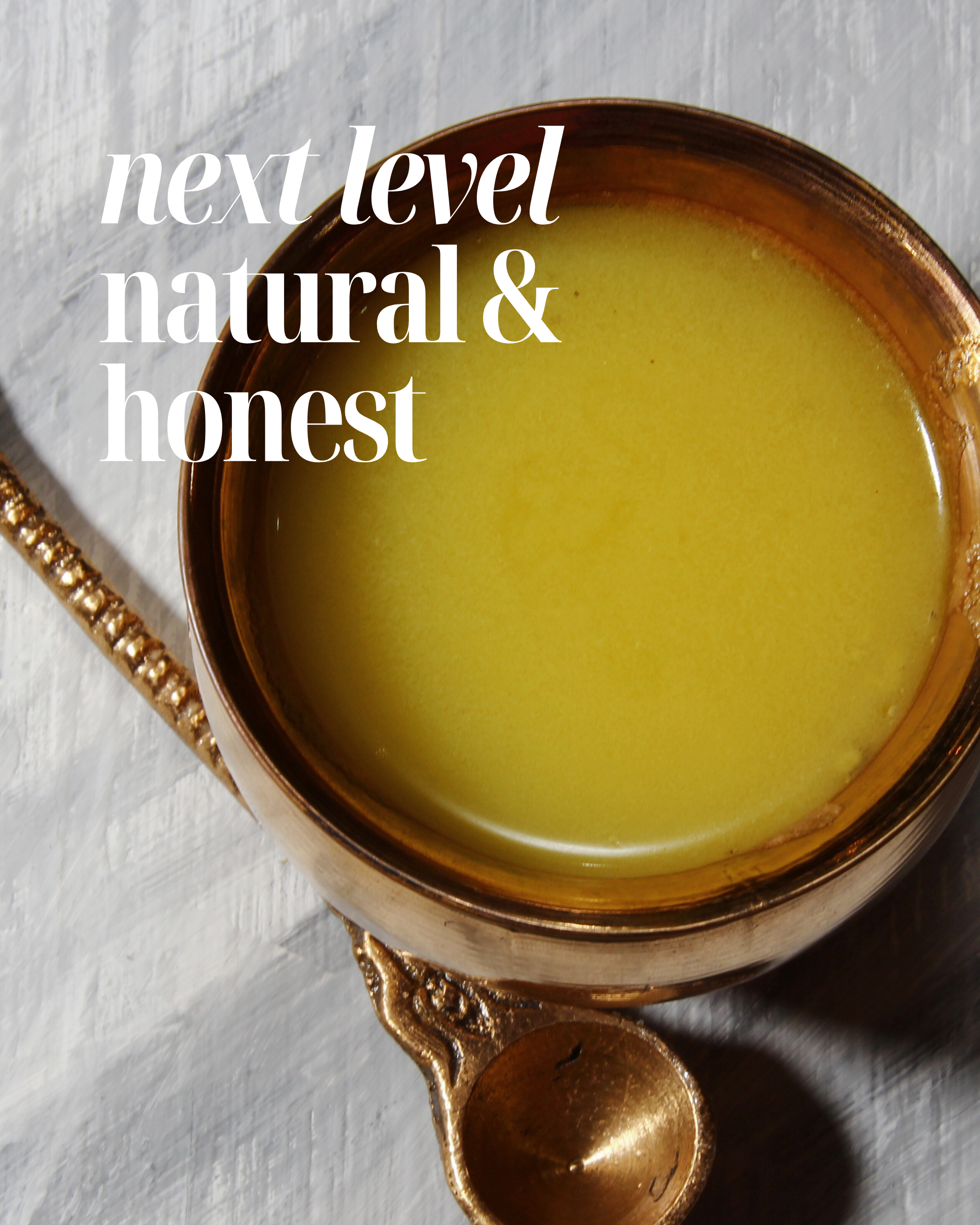 Copper bowl with ghee/clarified butter on a white background, text 'next level natural & honest' above.